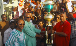 Handlers of Just Call Me Boss accepting the large winner’s trophy compliments of the Trophy Stall of Bourda Market. (Orlando Charles photo) 