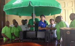 Nardeo Singh, Vice President of the Zara Group of Companies, hands over three of the 10 computer systems to Town Clerk Royston King, while staff of the Georgetown Mayor and City Council look on. 