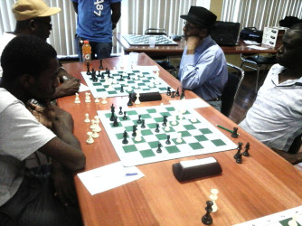 Clement Corlette (left foreground) leads the Forbes Burnham Memorial Chess with two rounds yet to play. Corlette smashed tournament favourite Anthony Drayton in his fifth round encounter to assume the lead. In the photo, Corlette opposes Plaisance’s Alexander Dun.