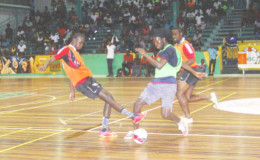 Daniel Favourite (green) of Festival City trying to evade the challenge of Bent Street’s Daniel Wilson (left) while Frank Crandon pursues during their team’s matchup in the GT Beer Futsal Championship