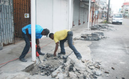 Workers removing concrete from blocking a drain in Robb Street yesterday to allow for it to be cleaned. Illegal structures like this one have contributed to the flooding in the city over the years.(Photo by Keno George)
