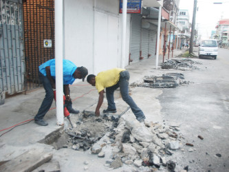 Workers removing concrete from blocking a drain in Robb Street yesterday to allow for it to be cleaned. Illegal structures like this one have contributed to the flooding in the city over the years.(Photo by Keno George)  