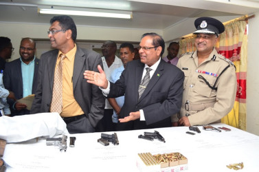 Prime Minister Moses Nagamootoo, Public Security Minister Khemraj Ramjattan and Police Commissioner Seelall Persaud during the inspection of the arms and ammunition collected under the current amnesty. (GINA photo) 