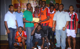 Captain of the victorious Bent Street side Daniel Wilson is all smiles as he collects the championship trophy from Banks DIH Limited GT Beer Brand Manager Jeff Clement (green) while Petra Organization Co-Director Troy Mendonca (2nd from right) and other members of the winning team and Banks DIH Limited look on
