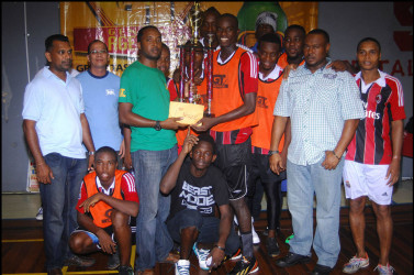 Captain of the victorious Bent Street side Daniel Wilson is all smiles as he collects the championship trophy from Banks DIH Limited GT Beer Brand Manager Jeff Clement (green) while Petra Organization Co-Director Troy Mendonca (2nd from right) and other members of the winning team and Banks DIH Limited look on 