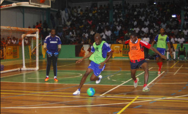 Sheldon Shepherd (green) of Sparta Boss trying to evade the challenge of Bent Street’s Amos Ramsay (orange) during their nail-biting clash in the GT Beer Futsal Championship at the Cliff Anderson Sports Hall