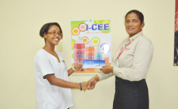Soroya Simmons (left) receives her sponsorship package from Jennifer Khan, Soft Drink Manager.