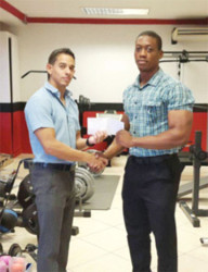 CAC Bound! Mr. Guyana, Kerwin Clarke collects his airfare compliments of CEO of Fitness Express, Jamie McDonald pictured at left.  