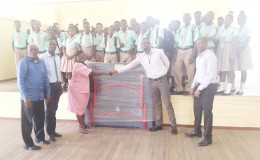 Director of Sports Chris Jones hands over the table to a representative of the Lodge Secondary School in the presence of teachers and officials while GTTA President Godfrey Monroe (far right) looks on.