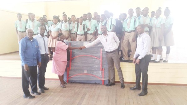 Director of Sports Chris Jones hands over the table to a representative of the Lodge Secondary School in the presence of teachers and officials while GTTA President Godfrey Monroe (far right) looks on. 