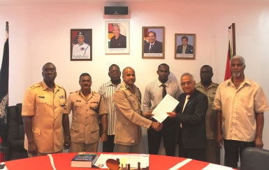  Commissioner of Police Seelall Persaud receives a copy of the “Rights of Arrested Persons” from Guyana Bar Association President Christopher Ram in the presence of several senior police officials. (Guyana Police Force photo)  