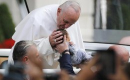 Pope Francis kisses a child who was lifted up to him while he rode in the popemobile to Independence Hall in Philadelphia (Reuters/Jim Bourg)