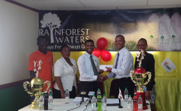 AAG President Aubrey Hutson (2nd from right) collects the sponsorship cheque from Banks DIH Limited Rainforest Waters and PowerAde Brand Manager Errol Nelson while other members of the launch party look on.
