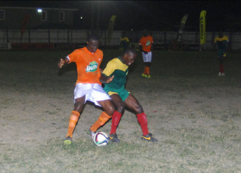 Fruta Conqueror’s Dennis Edwards (left) trying to shield the ball from a GDF player during their GFF Stag Beer Elite League matchup at the Tucville Community ground