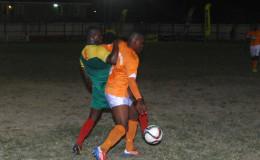 Jermin Junior of Fruta Conquerors (orange) battling to maintain control of the ball while being challenged by a GDF player during their team’s matchup in the GFF Stag Beer Elite League at the Tucville Ground