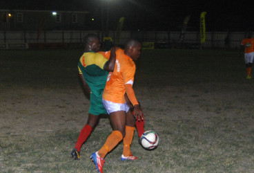 Jermin Junior of Fruta Conquerors (orange) battling to maintain control of the ball while being challenged by a GDF player during their team’s matchup in the GFF Stag Beer Elite League at the Tucville Ground