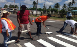 Massy Industries Berbice staff members painting a pedestrian crossing