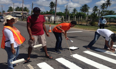 Massy Industries Berbice staff members painting a pedestrian crossing