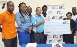 All smiles! The elated GRFU president, Peter Green (left) accepts the sponsorship cheque from GTT’s Senior Marketing Officer Anjanie Hackett yesterday in the presence of players, other GRFU executive members and staff of the company.
