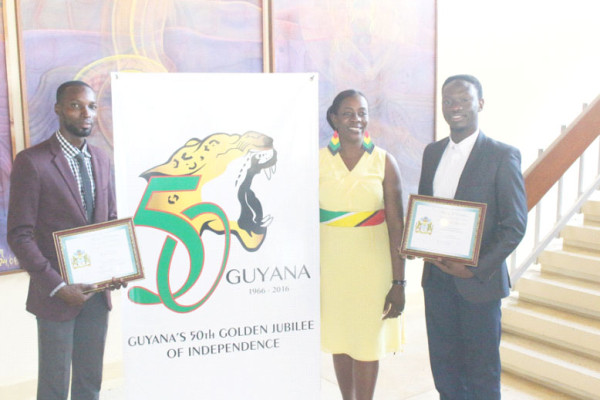 Golden Jubilee logo: The winners of Guyana’s 50th Independence Anniversary logo competition, Christopher Taylor (right) and Compton Babb (left), pose with Junior Education Minister Nicolette Henry in front of their winning design. (Photo by Keno George)  