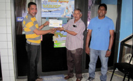 Mark De Freitas, manager of Survival Travel Agency hands over the tickets to Guyana Floodlights Softball Cricket Association (GFSCA) president Ramchand Ragbeer while GFSCA member Surendra Nauth at right looks on.