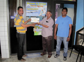 Mark De Freitas, manager of Survival Travel Agency hands over the tickets to Guyana Floodlights Softball Cricket Association (GFSCA) president Ramchand Ragbeer while GFSCA member Surendra Nauth at right looks on.
