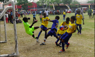 Action between Stella Maris (in yellow) and Enterprise Primary (in blue) during their matchup in the Courts Pee Wee Football Championship at the Thirst Park ground yesterday. 