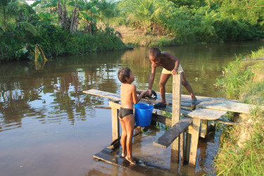 Two boys gave up a portion of their afternoon’s play to fetch water from the canal near their Hubu Backdam home at Parika as the area has been experiencing a water shortage for quite some time now. (Photo by Keno George) 