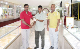 Georgetown Floodlight Softball Cricket Association member (GFSCA) Dharam Persaud accepts the gold bracelets from proprietor of Steve’s Jewellery Steve Narine as GFSCA vice president Ricky Deonarain watches on.