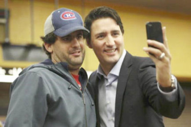 Liberal leader and prime minister-designate Justin Trudeau takes a selfie while greeting people at a subway station in his riding in Montreal, Quebec, October 20, 2015.  Reuters/Chris Wattie 