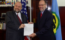 Perry Holloway (left) presenting his credentials to Caricom Secretary General Irwin LaRocque (Caricom photo)