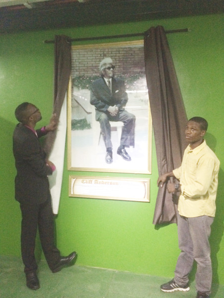 Director of Sport, Chris Jones, (left) and Clive ‘The Punisher’ Atwell unveiling a portrait of Cliff Anderson at the Cliff Anderson Sports Hall Thursday night.
