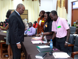 Minister of State, Joseph Harmon (left)  interacting with some of the public servants  