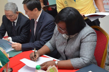 Chinese Ambassador Zhang Limin (left) and Minister within the Ministry of Public Health Dr. Karen Cummings (right) exchanging documents related to the donation of medical equipment from the Chinese Government. (GINA photo)