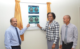 Governor of the BoG Gobind Ganga (left) and Minister Annette Ferguson (centre) unveiling the two commemorative stamps for the bank’s 50th anniversary as Post Master General Abdul Hassan looks on.
