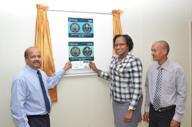 Governor of the BoG Gobind Ganga (left) and Minister Annette Ferguson (centre) unveiling the two commemorative stamps for the bank’s 50th anniversary as Post Master General Abdul Hassan looks on. 