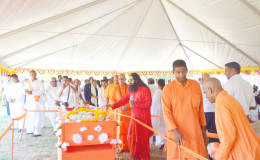 Last rites: Swami Vidyanandaji Maharaj, spiritual director of the Cove and John Ashram and the America Sevashram Sangha was cremated yesterday at a ceremony which saw a large gathering at the East Coast institution. The Swami died last week in the United States and his body was returned to Guyana. In this photo final respects are being paid by the many who attended. (Dhanash Ramroop photo)