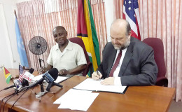 Minister of Foreign Affairs Carl Greenidge and US Ambassador Perry Holloway during the signing yesterday. 
