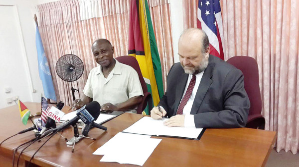 Minister of Foreign Affairs Carl Greenidge and US Ambassador Perry Holloway during the signing yesterday. 