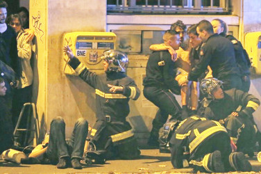French fire brigade members aid an injured individual near the Bataclan concert hall following fatal shootings in Paris, November 13, 2015. REUTERS/Christian Hartmann
