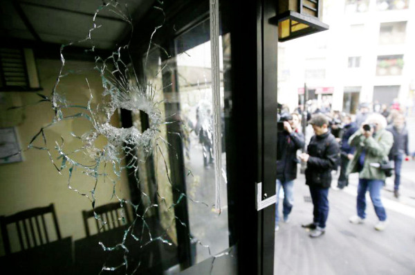Journalists work outside a restaurant where bullet impacts are seen in the shop window the day after a series of deadly attacks in Paris, France, November 14, 2015. (Reuters/Gonzalo Fuentes)
