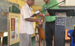 Minister of State, Joseph Harmon (right) handing over the cheque to Mr. Bowman, resident of Crane Housing Scheme.  (Ministry of the Presidency photo)