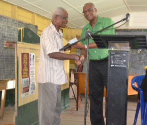Minister of State, Joseph Harmon (right) handing over the cheque to Mr. Bowman, resident of Crane Housing Scheme.  (Ministry of the Presidency photo) 