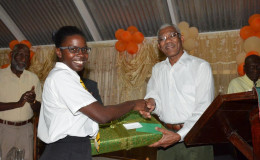 Elisa Hamilton being presented with a laptop computer by President David Granger (Ministry of the Presidency photo)
