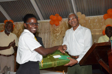 Elisa Hamilton being presented with a laptop computer by President David Granger (Ministry of the Presidency photo) 