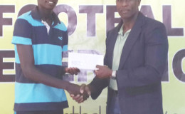 Daniel Wilson (left) collecting the airline ticket from GFF First Vice-President Bruce Lovell
