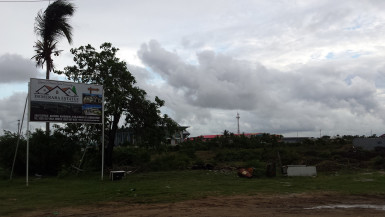 The site for the Sun and Sand Hotel is barren with only garbage littering the site and a lone container to the right. The sign is no longer there and instead a billboard for Demerara Estates has been erected. 