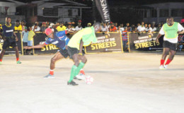East Front Road’s Kacy John (blue vest) trying to maintain possession of the ball while being challenged by West Front Road’s Hubert Pedro while Randolph Wagner of Wets Front Road look on during their team’s matchup in the Guinness of the Streets Georgetown Zone at the Albouystown Tarmac