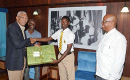 President David Granger presents Terron Alleyne with a new laptop computer, as Minister of Finance, Winston Jordan (right), and the lad’s father, Terrence Alleyne, looks on. (GINA photo)
​
