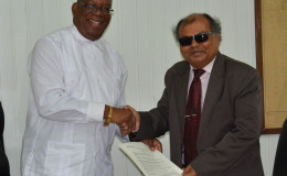 Minister of Finance Winston Jordan (left) and Fedders Lloyd Country Representative Ajay Jha shaking hands on the deal. (Ministry of Finance photo)
